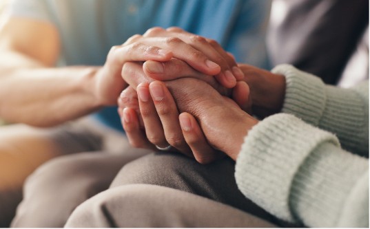 Close-up of two people's hands clasped together in a comforting gesture, suggesting support or empathy.