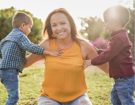 Yon manman souriyan k ap pase tan deyò ak de pitit li yo, sa reprezante sipò ak gerizon familyal.